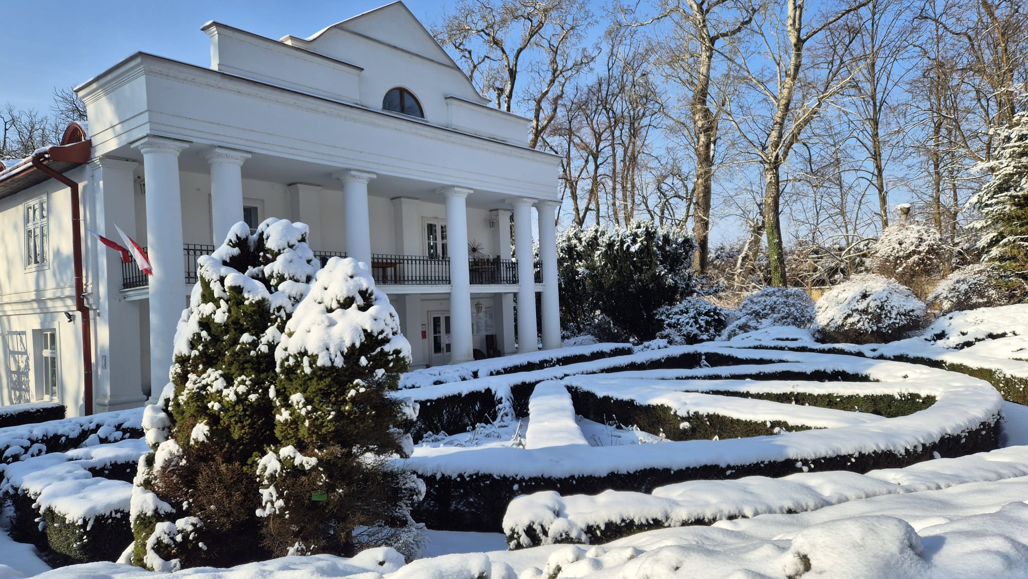 Zdjęcie frontonu pałacu i zaśnieżonej jego okolicy